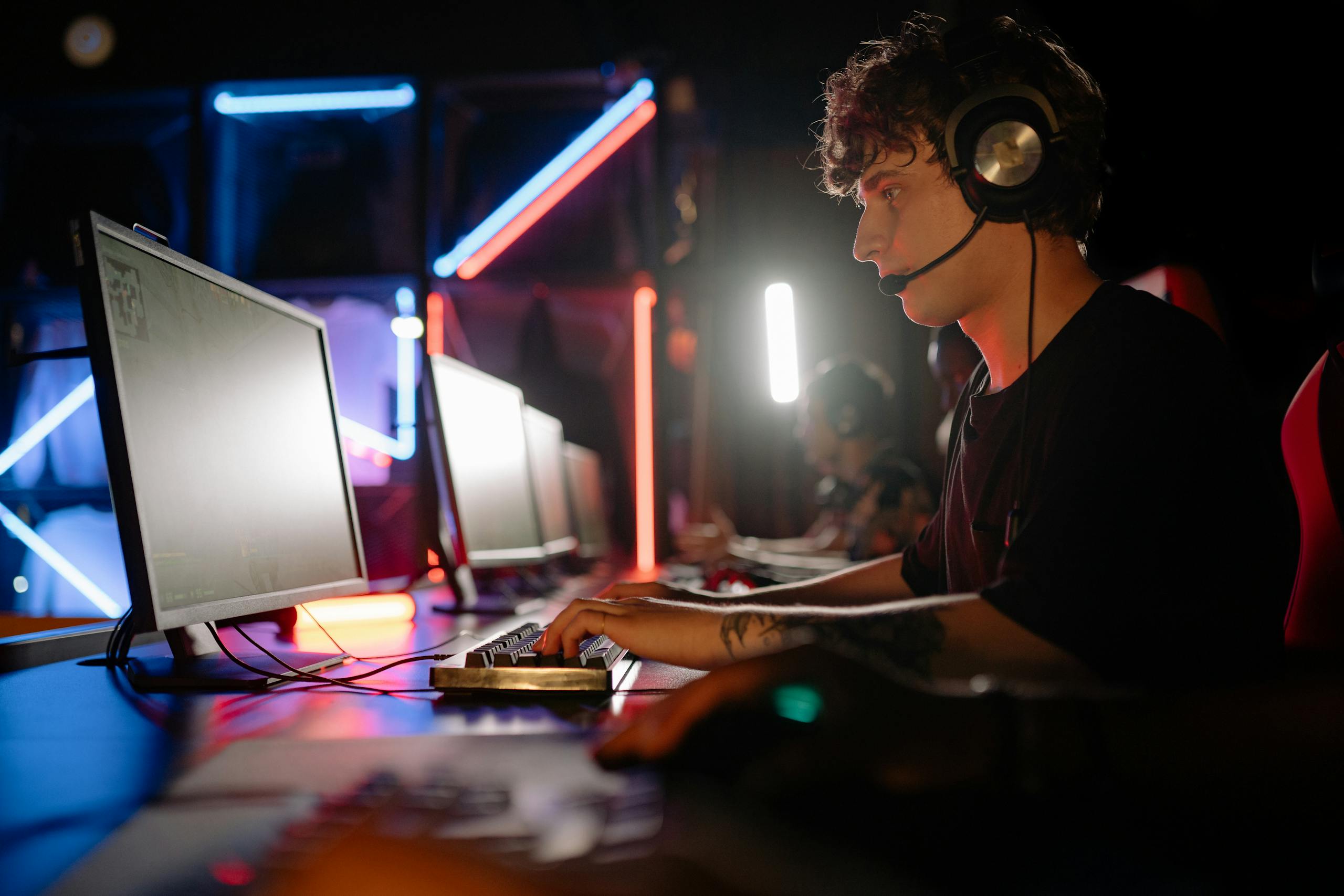 Young man engaged in an immersive gaming experience at a neon-lit PC setup.